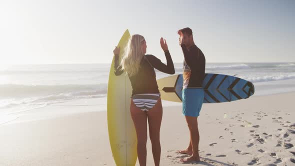 Caucasian couple holding surfboards on the beach