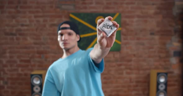 Young Caucasian Man Holding Condoms with Stop Aids Inscription on Wrap