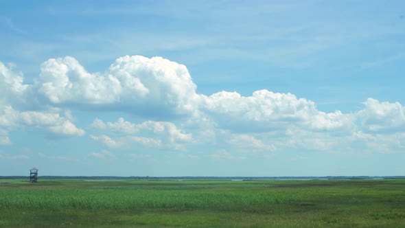 Time lapse of beautiful white fasting clouds and sky in sunny day at lake Liepaja birdwatching tower