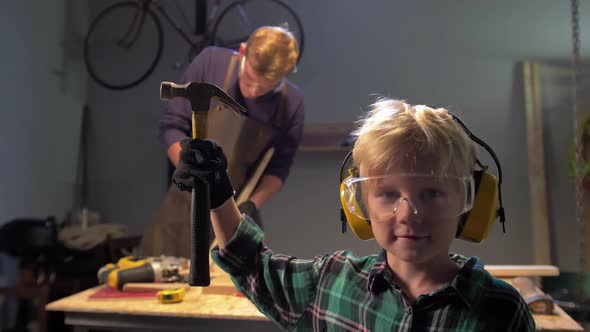 Boy in Glasses Stands with Hammer and Looks at the Camera, Slow Motion