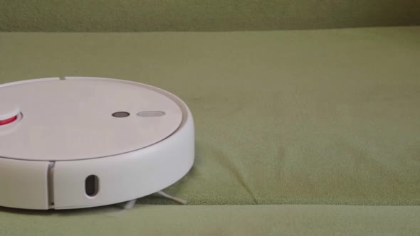 Robot vacuum cleaner vacuuming the bed in the bedroom. Smart home with automated devices