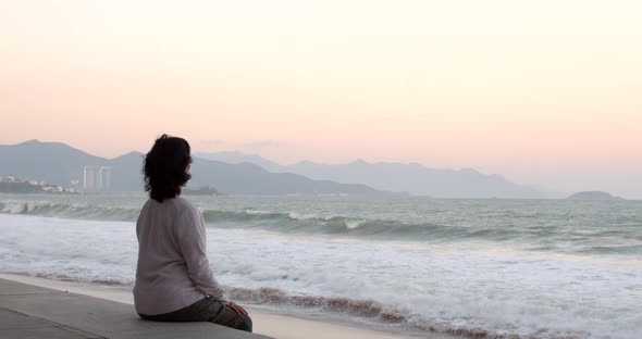 An Aged Woman Wearing a Protective Mask is Doing Exercises and the Sea View Wearing a Covid19 Mask