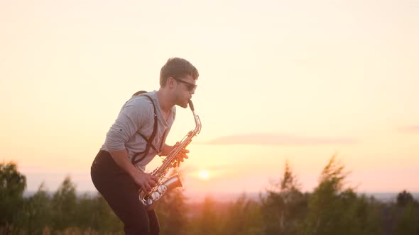 Portrait of Bearded Musician in Sunglasses and Gray Shirt Performs His Part on Beautiful Shiny