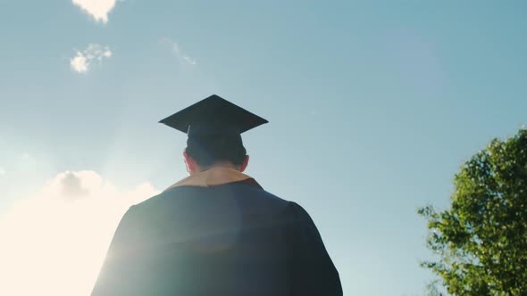 Rear View of the University Graduates Student at Silhouette Sunset Goes on the Road