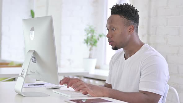 Ambitious Casual African Man Celebrating Success on Desktop
