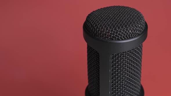 Studio Condenser Microphone Rotates on Red Background with Place for Text