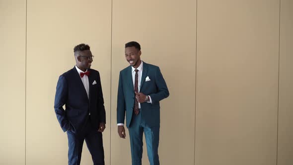 Cheerful groom and best man posing in room