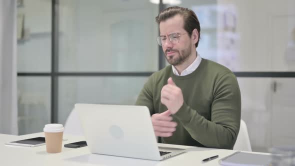 Young Businessman Having Wrist Pain While Using Laptop in Office