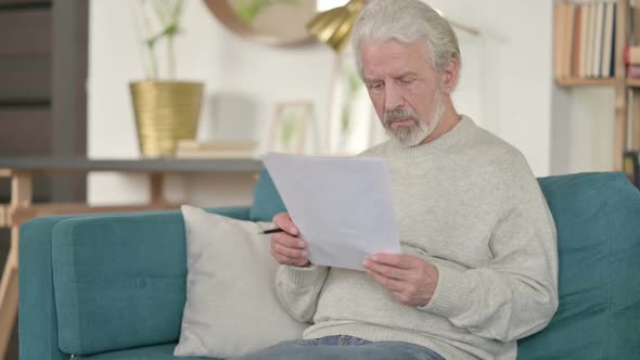 Old Man Reading Documents and Reacting to Loss