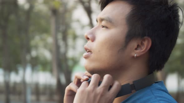 A sporty man wearing headphone while standing and jogging at the park.