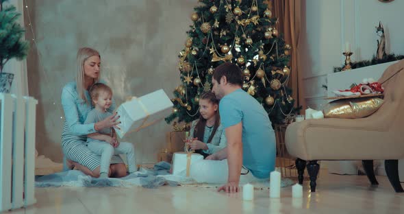 Children with Parents Open Christmas Gifts at the Christmas tree.Christmas Tree Is Beautifully