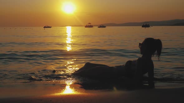 Beautiful Young Girl Lying on the Beach at Sunset. Girl on Vacation Relaxing on the Beach and