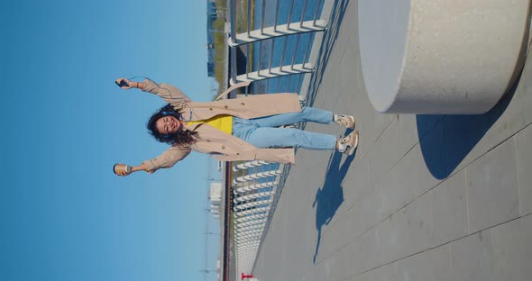 Great News  an Asian Woman with a Smartphone in Her Hand is Jumping with Happiness