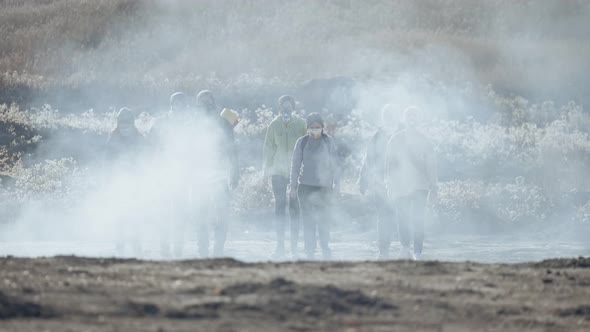 Group of Young People in Gas Mask Going Through the Toxic Smoke