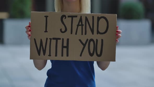 I STAND WITH YOU on a Cardboard Poster in the Hands of White Female Protester Activist. Closeup of
