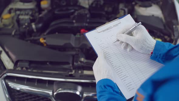 Asian automotive mechanic man hold checklist clipboard check up engine.