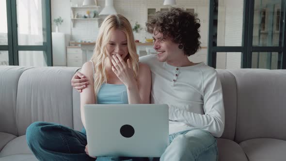 Happy Bonding Family Couple Resting on Comfortable Sofa Watching Funny Films on Computer Shopping or