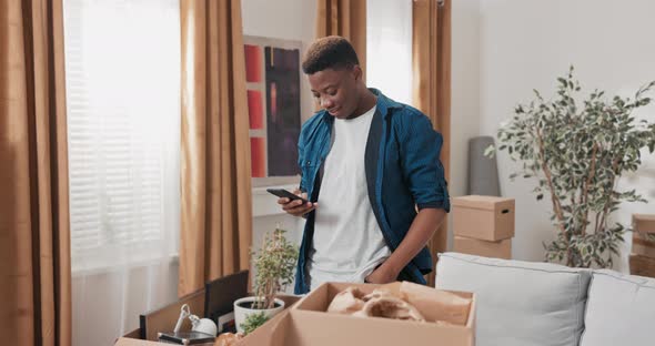 Handsome Guy Hangs Out in New Apartment After Movein Unpacks Cardboard Boxes of Packed Stuff Writes