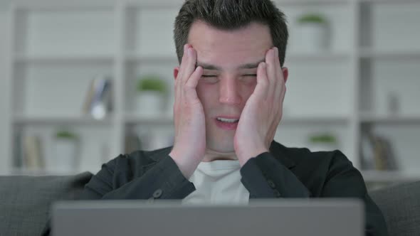 Portrait of Young Male Designer with Laptop Having Headache 