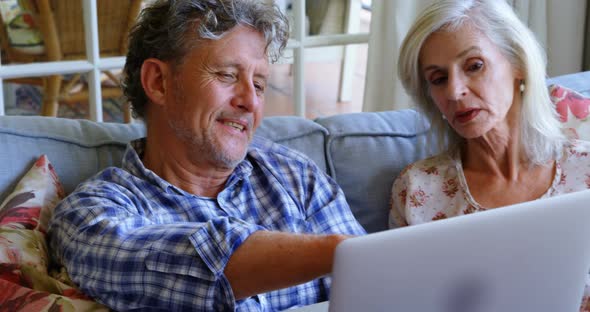 Senior couple discussing over laptop on sofa 