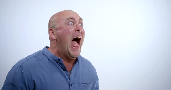 Crazy Drunk Bald Man in a Blue Shirt Makes a Face and Wildly Screams Into the Void To Get His Tongue