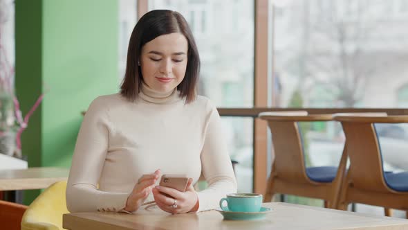 Happy Woman Swiping Smartphone Screen and Making Victory Gesture