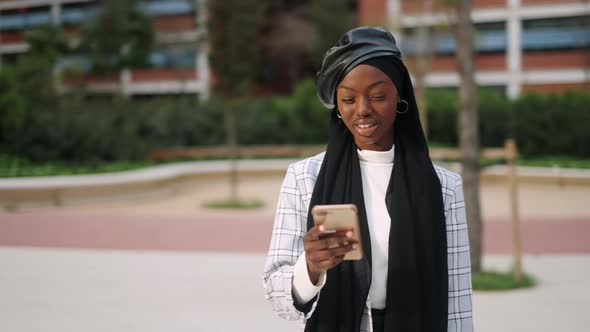 Muslim Woman Using Smartphone on Street