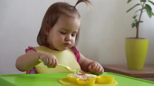 Close Up of Lovely Baby Girl Eating Have Breakfast Eggs Vegetables Sausage By Herself at Home