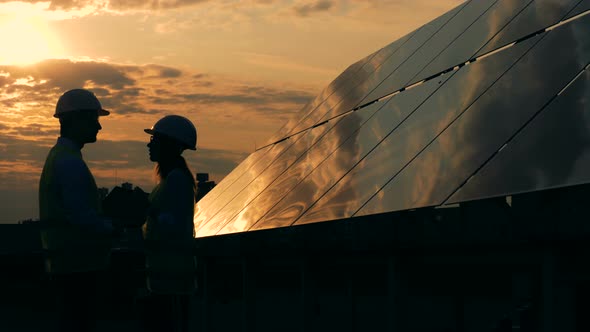 Solar Panels and Two Workers Silhouettes Talking