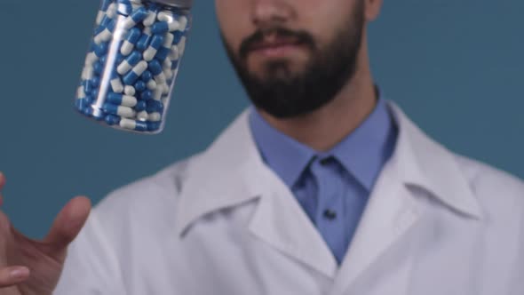 Doctor in White Coat Tossing Jar of Pills