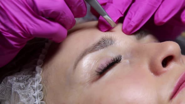 correction and shaping of women's eyebrows in a beauty salon with a sharp knife. eyebrow trimming