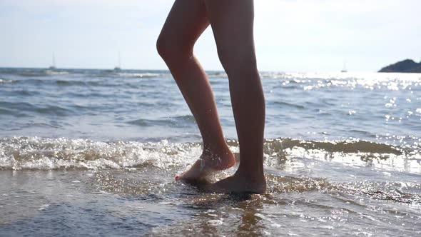 Female Feet Walking on Sea Water at Beach with Seascape and Waves at Background