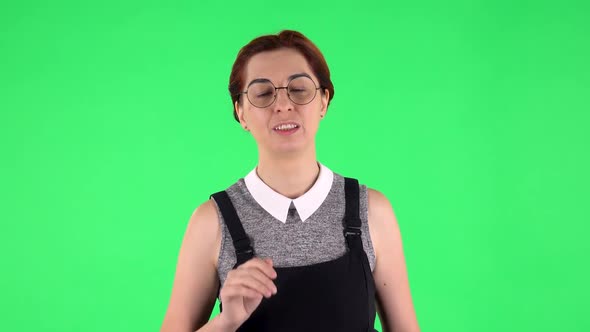 Portrait of Funny Girl in Round Glasses Is Waving Hand and Showing Gesture Come Here. Green Screen