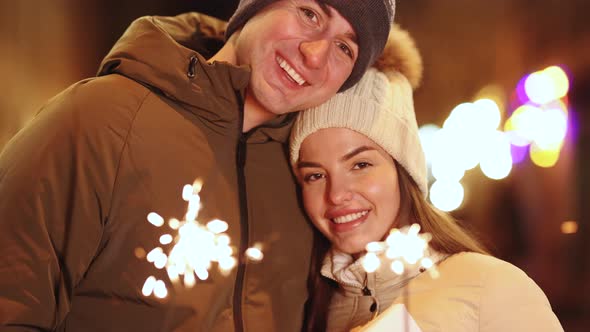 Two People Celebrate New Year on The Street Hugging Holding Sparklers