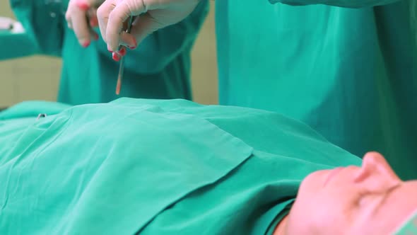 Team of surgeons working on an unconscious female patient