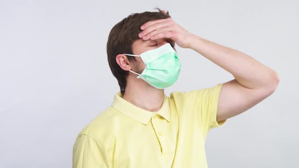 Sick Person in Protective Respiratory Mask and Yellow Shirt Touching Forehead with Arm To Check Body