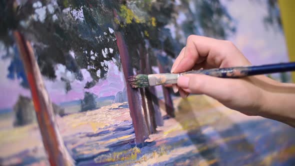 The artist s hand with a brush glides over the canvas of the painting