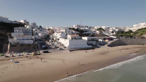 Cinematic aerial panning view of Burgau beach and whitewashed buildings, Algarve Portugal.