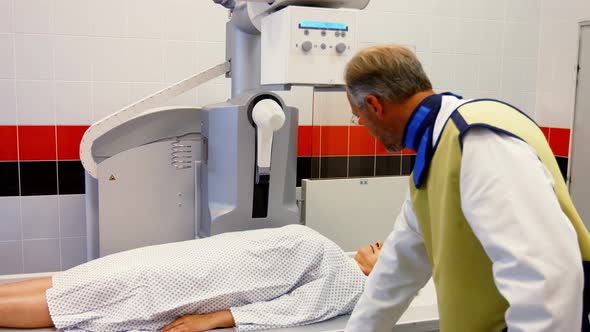 Male doctor sets up the machine to x-ray a female patient