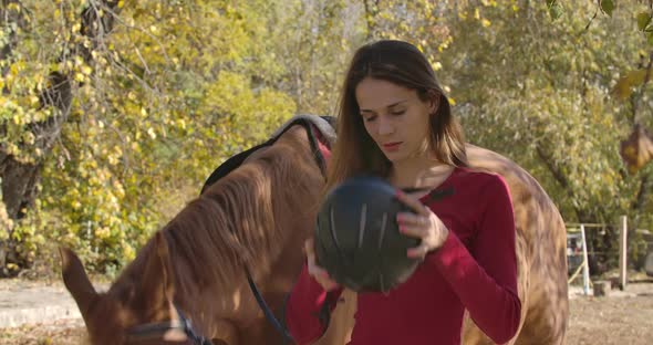 Professional Female Caucasian Jockey Putting on Horse Riding Helmet