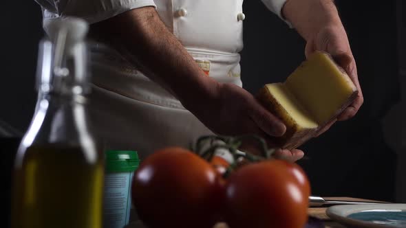 Cook Holds Head Cheese in Hands on Table Blurry Olive Oil, Tomatoes and Spices