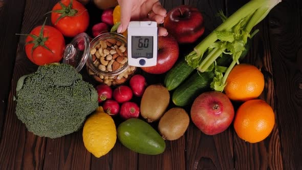 Lots of Vegetables and Fruits and a Blood Sugar Meter on a Wooden Background
