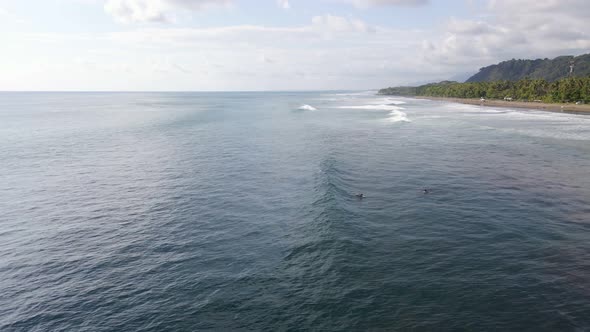 Surfer catching a big wave before falling off the board at Dominical Beach, Costa Rica. Aerial wide