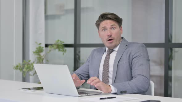 Middle Aged Man feeling Shocked while using Laptop in Office