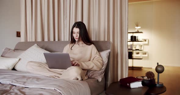 Business Woman Wear Headset Video Conference Calling on Laptop Computer on a Bed