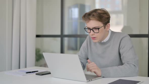 Young Man Reacting to Loss While Using Laptop in Modern Office