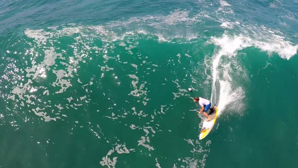 Aerial view of a man sup stand-up paddleboard surfing in Hawaii.