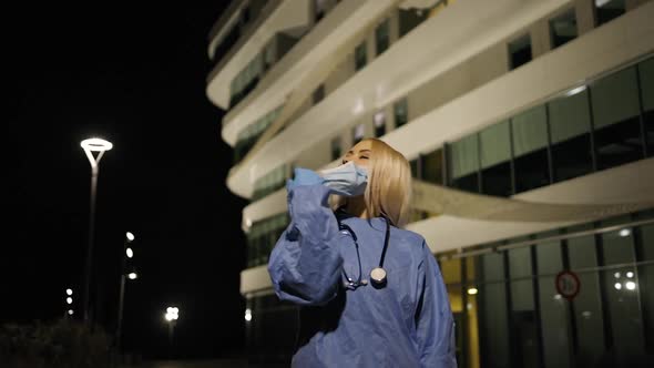 Young Female Medical Intern Takes Off Medical Mask During Night Shift