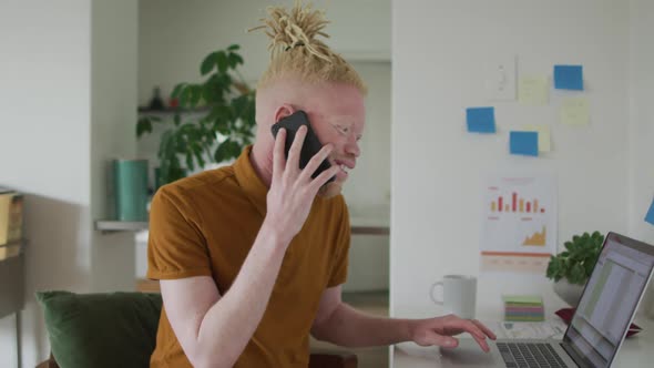 Albino african american man with dreadlocks working, using laptop and smartphone