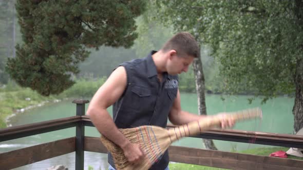 A Male Guitarist Holds a Broom Like a Guitar and Shows That He is Playing Music